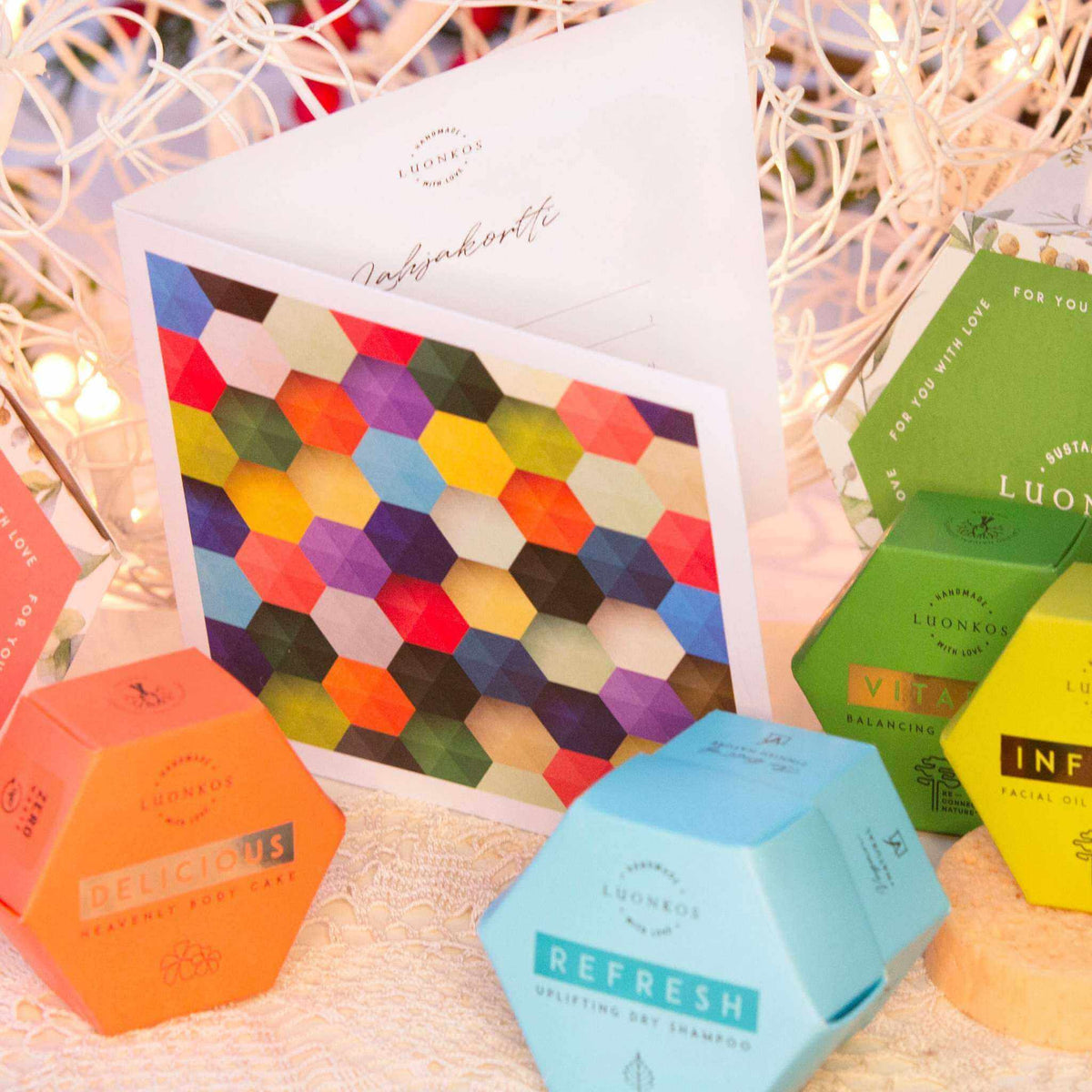 Colorful hexagonal Luonkos Lahjakortti gift card with natural cosmetics packaging and decorative lights background
